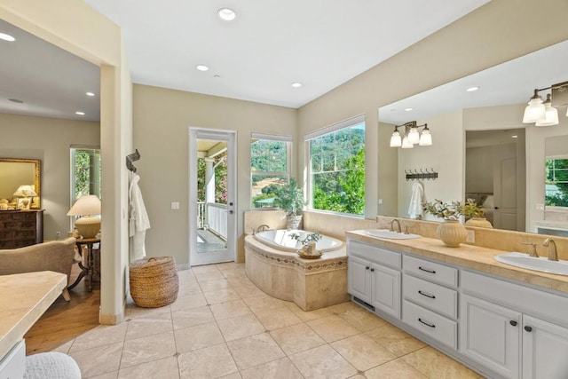 bathroom featuring tile patterned flooring, tiled tub, and vanity