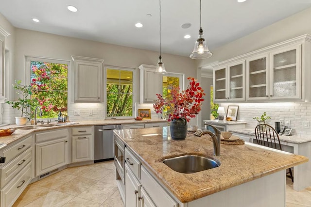 kitchen with white cabinetry, a kitchen island with sink, dishwasher, and sink