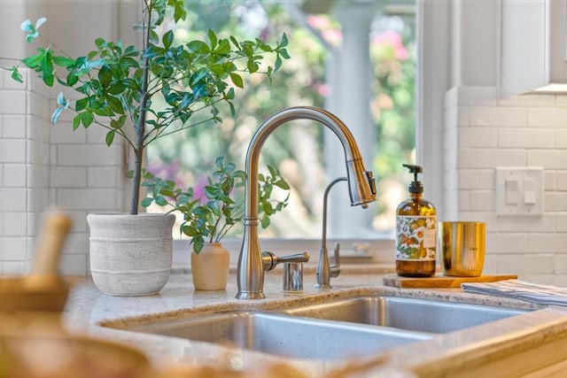 room details with light stone countertops, tasteful backsplash, and sink