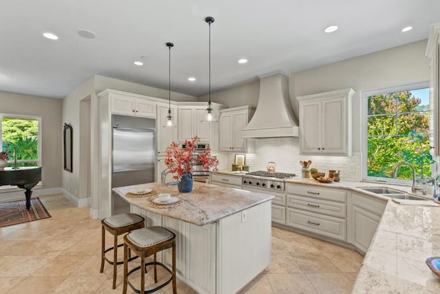 kitchen with stainless steel appliances, wall chimney range hood, white cabinets, and sink