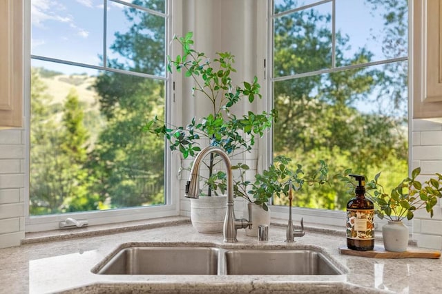 details with light stone counters, decorative backsplash, and sink