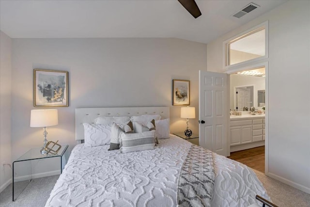 bedroom with ceiling fan, connected bathroom, vaulted ceiling, and carpet