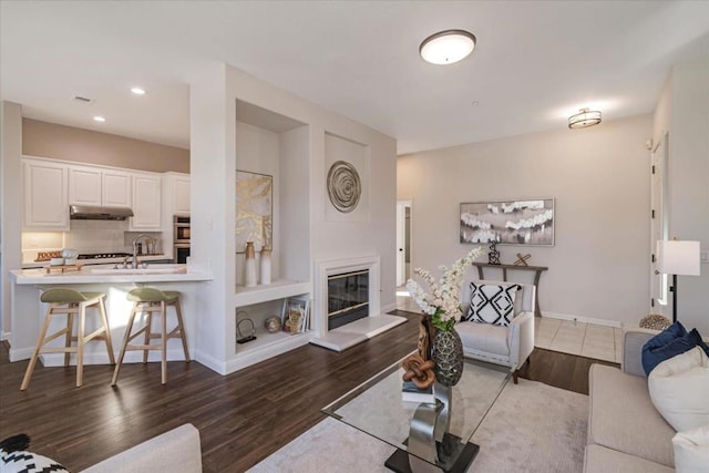 living room featuring built in shelves, sink, and hardwood / wood-style flooring