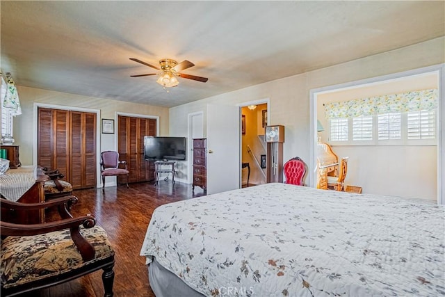 bedroom featuring ceiling fan, dark wood-type flooring, and multiple closets