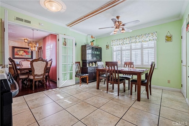 tiled dining area featuring ornamental molding and ceiling fan with notable chandelier