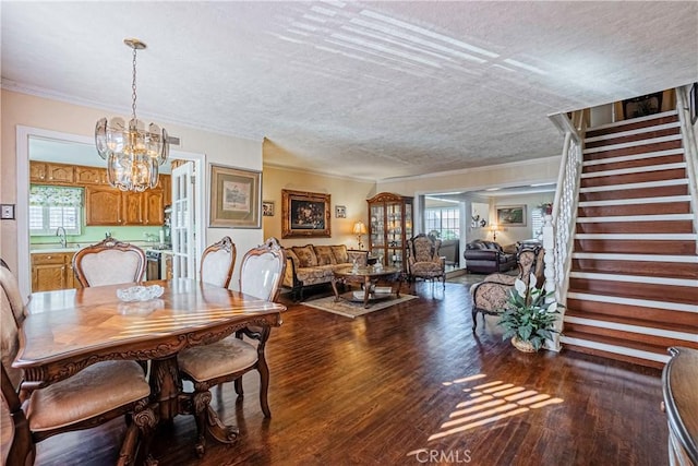 dining space with a textured ceiling, hardwood / wood-style floors, an inviting chandelier, and sink