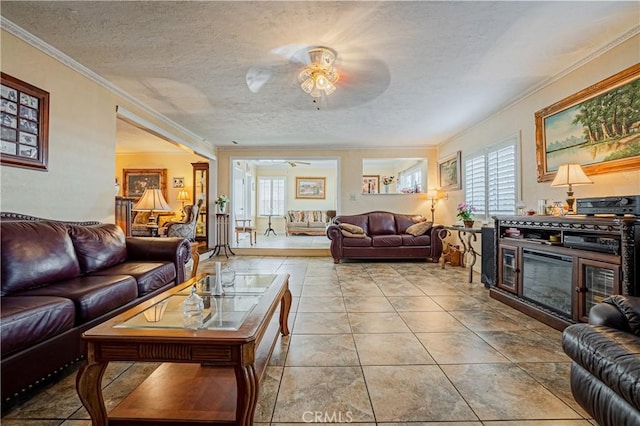 tiled living room featuring a textured ceiling, ceiling fan, and crown molding