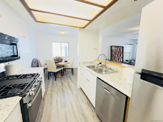 kitchen featuring light stone countertops, light hardwood / wood-style flooring, stainless steel appliances, white cabinetry, and sink