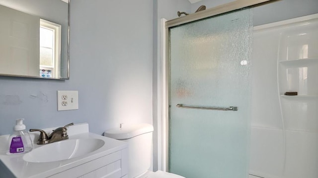 bathroom with a shower with shower door, vanity, and toilet