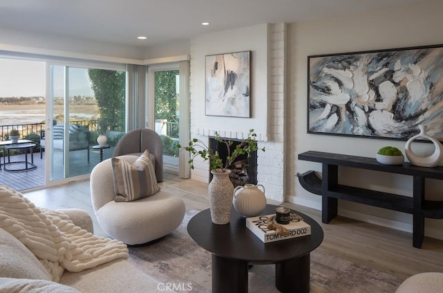 living room featuring a brick fireplace and light hardwood / wood-style flooring