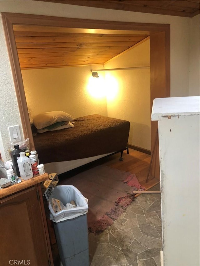 bedroom with lofted ceiling, stone finish floor, and wood ceiling