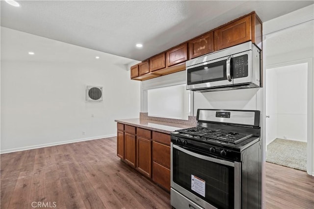 kitchen featuring appliances with stainless steel finishes, hardwood / wood-style floors, and a textured ceiling