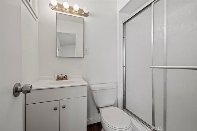 bathroom with toilet, a shower with door, and vanity