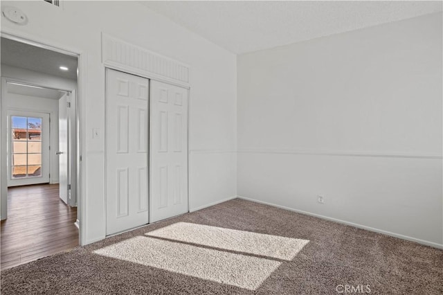 unfurnished bedroom featuring dark colored carpet and a closet