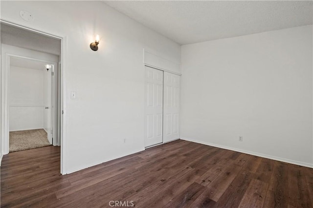 unfurnished bedroom featuring a closet and dark hardwood / wood-style flooring