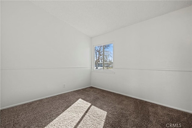 spare room featuring lofted ceiling, dark carpet, and a textured ceiling