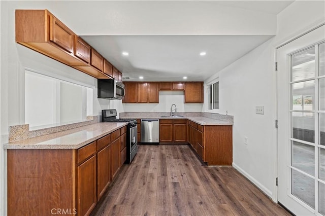 kitchen featuring light stone counters, stainless steel appliances, dark wood-type flooring, and sink