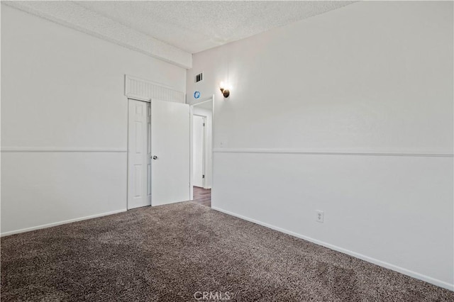 empty room with a textured ceiling and carpet flooring