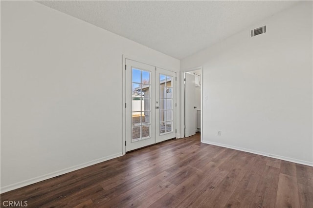 spare room featuring a textured ceiling, french doors, and dark hardwood / wood-style floors