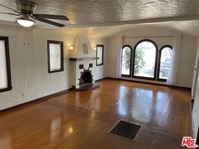 interior space with lofted ceiling, wood-type flooring, a large fireplace, and ceiling fan