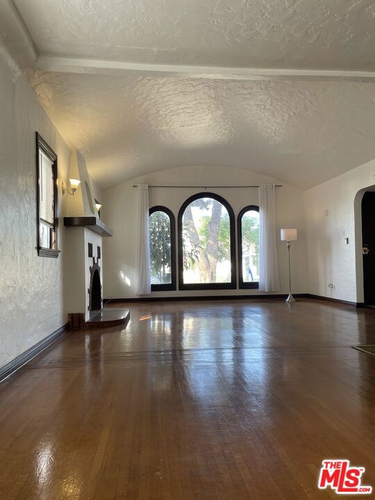 interior space with dark hardwood / wood-style flooring, vaulted ceiling, and a textured ceiling