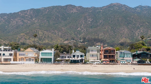 view of swimming pool featuring a water and mountain view and a view of the beach