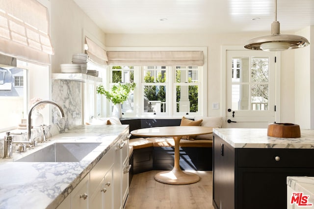 kitchen featuring sink, light wood-type flooring, breakfast area, and light stone countertops