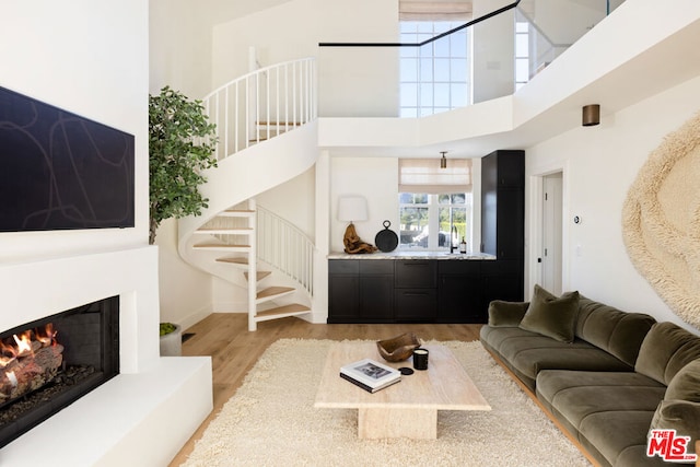 living room with a towering ceiling, light hardwood / wood-style floors, and sink