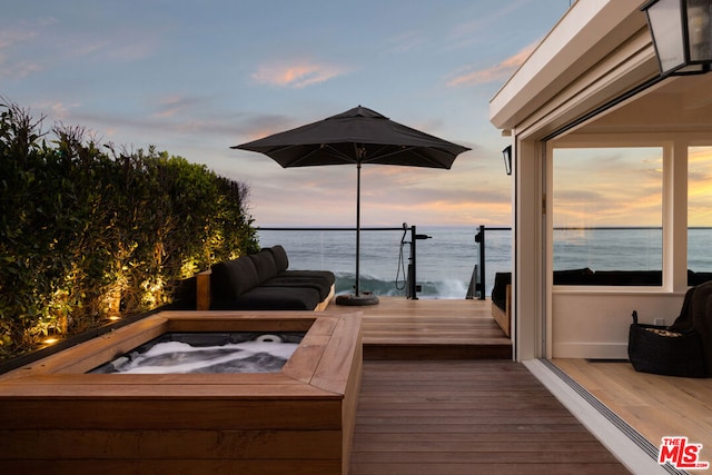 deck at dusk featuring a water view