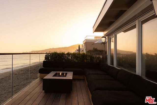 deck at dusk featuring an outdoor living space with a fire pit and a water and mountain view