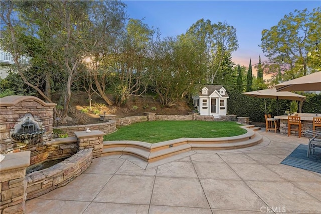 patio terrace at dusk featuring an outbuilding