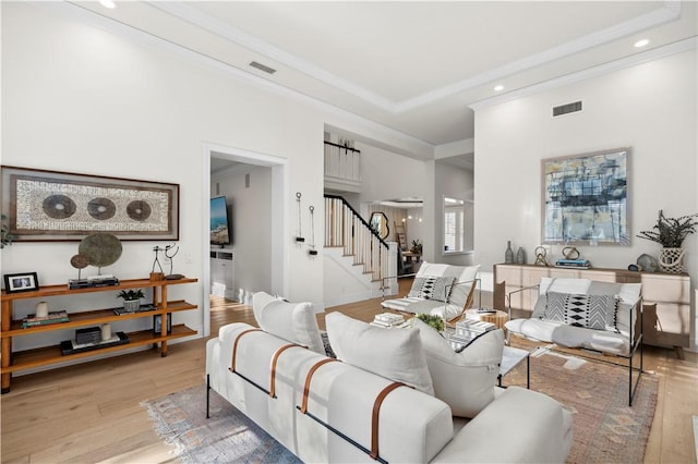 living room with light wood-type flooring and crown molding