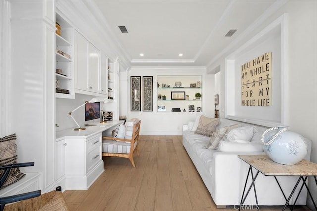 living room featuring light hardwood / wood-style floors, ornamental molding, built in shelves, and built in desk