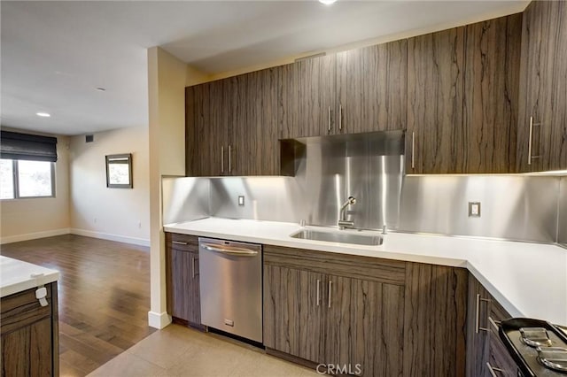 kitchen featuring tasteful backsplash, dishwasher, sink, and light hardwood / wood-style flooring