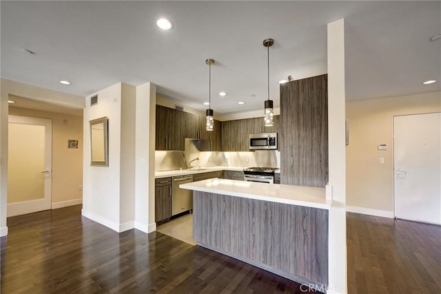 kitchen with kitchen peninsula, appliances with stainless steel finishes, backsplash, and dark hardwood / wood-style flooring