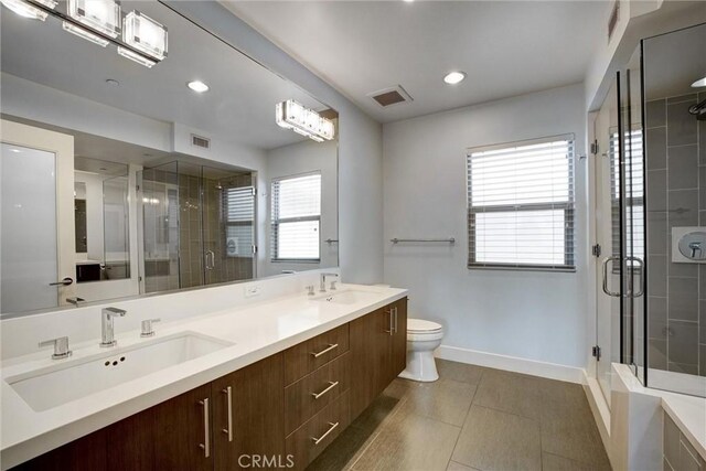 bathroom featuring toilet, tile patterned flooring, a shower with door, and vanity