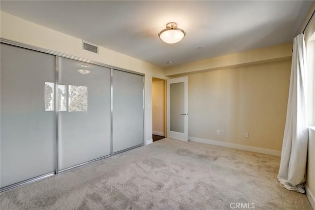 unfurnished bedroom featuring light carpet and a closet