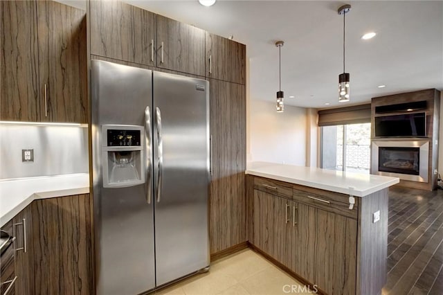 kitchen featuring hanging light fixtures, stainless steel fridge with ice dispenser, and kitchen peninsula