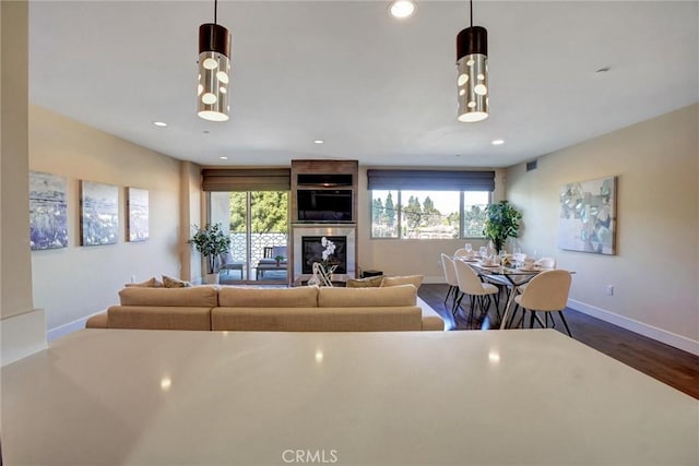 living room with visible vents, baseboards, dark wood-type flooring, a fireplace, and recessed lighting