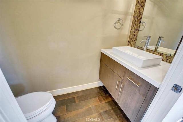 half bathroom featuring toilet, vanity, and baseboards