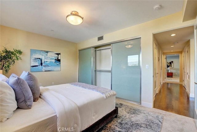 bedroom featuring wood finished floors, a closet, baseboards, and visible vents
