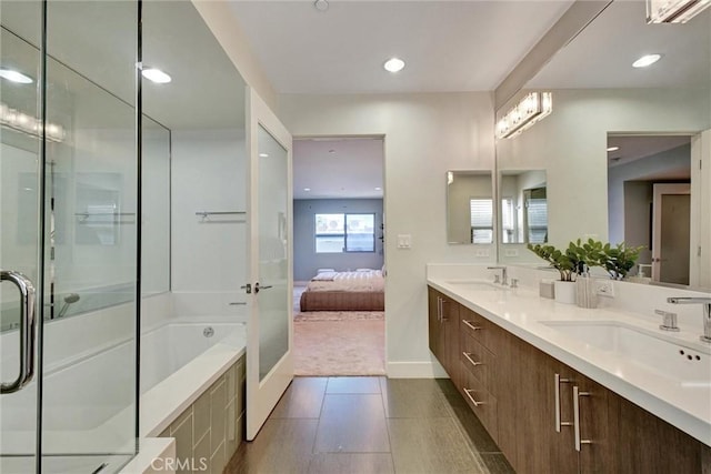 ensuite bathroom with a shower stall, double vanity, a sink, and a garden tub