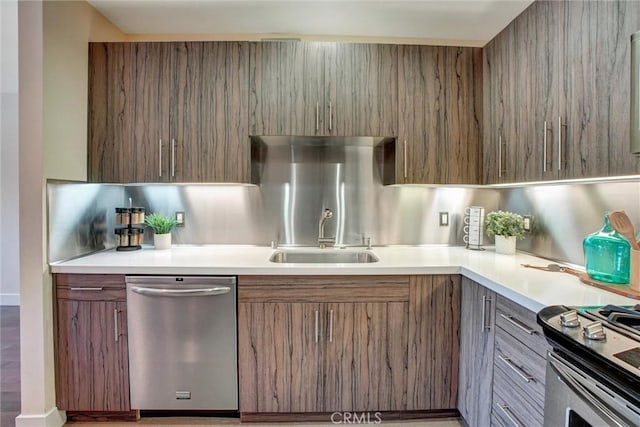 kitchen with appliances with stainless steel finishes, light countertops, brown cabinets, and a sink