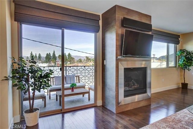 living room with a glass covered fireplace, baseboards, and wood finished floors