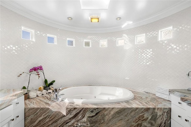 bathroom with ornamental molding, tiled tub, and vanity