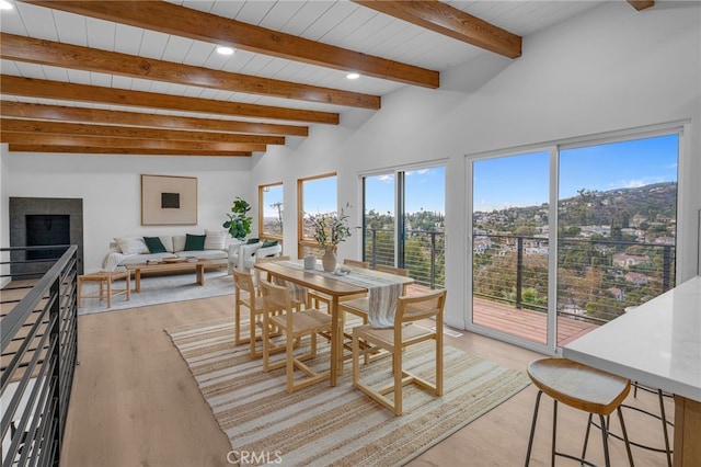 sunroom featuring a tiled fireplace, lofted ceiling with beams, and wooden ceiling