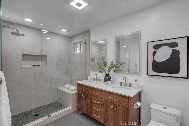 bathroom with vanity, toilet, tiled shower, and tile patterned floors