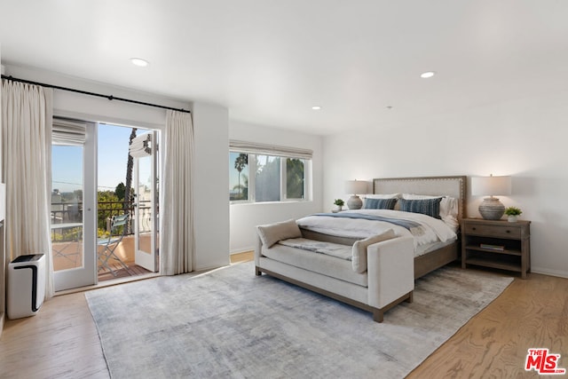 bedroom with multiple windows, access to outside, and light hardwood / wood-style flooring