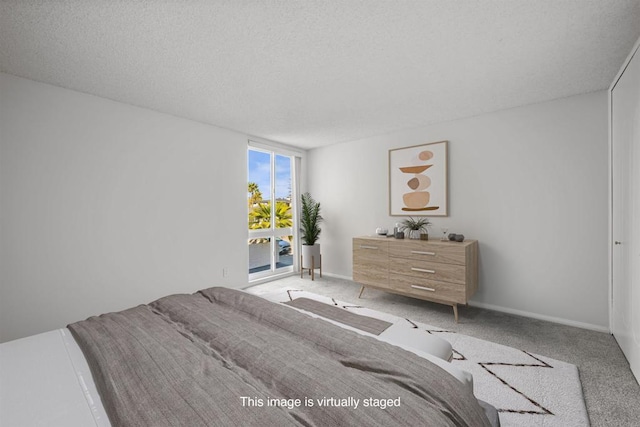 bedroom with access to exterior, a textured ceiling, baseboards, and carpet floors