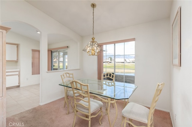 carpeted dining area featuring a healthy amount of sunlight, vaulted ceiling, and a notable chandelier